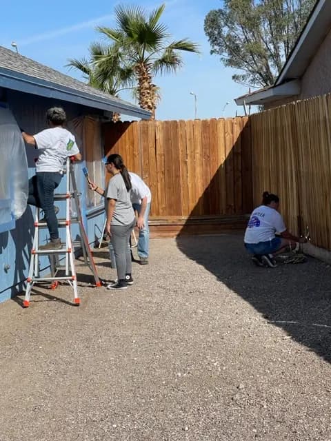 Volunteers paint the exterior of a home.