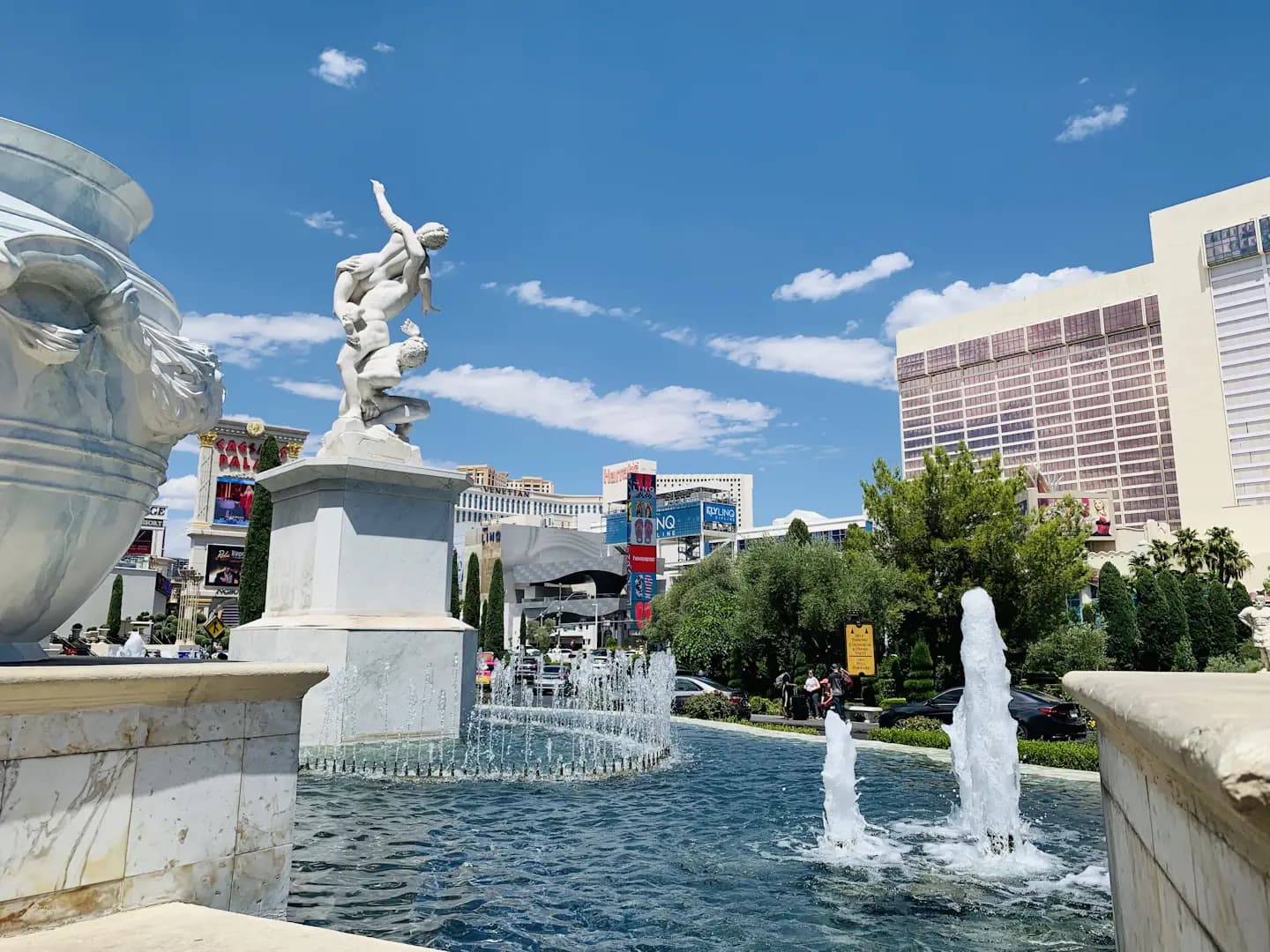 Turquoise fountain and white statues along the Las Vegas Strip under blue sky