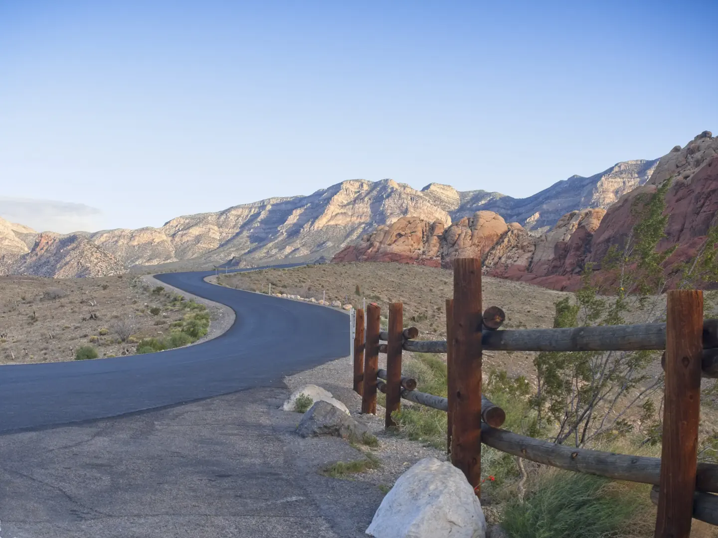Curving road through Red Rock Canyon with sandstone peaks and blue sky